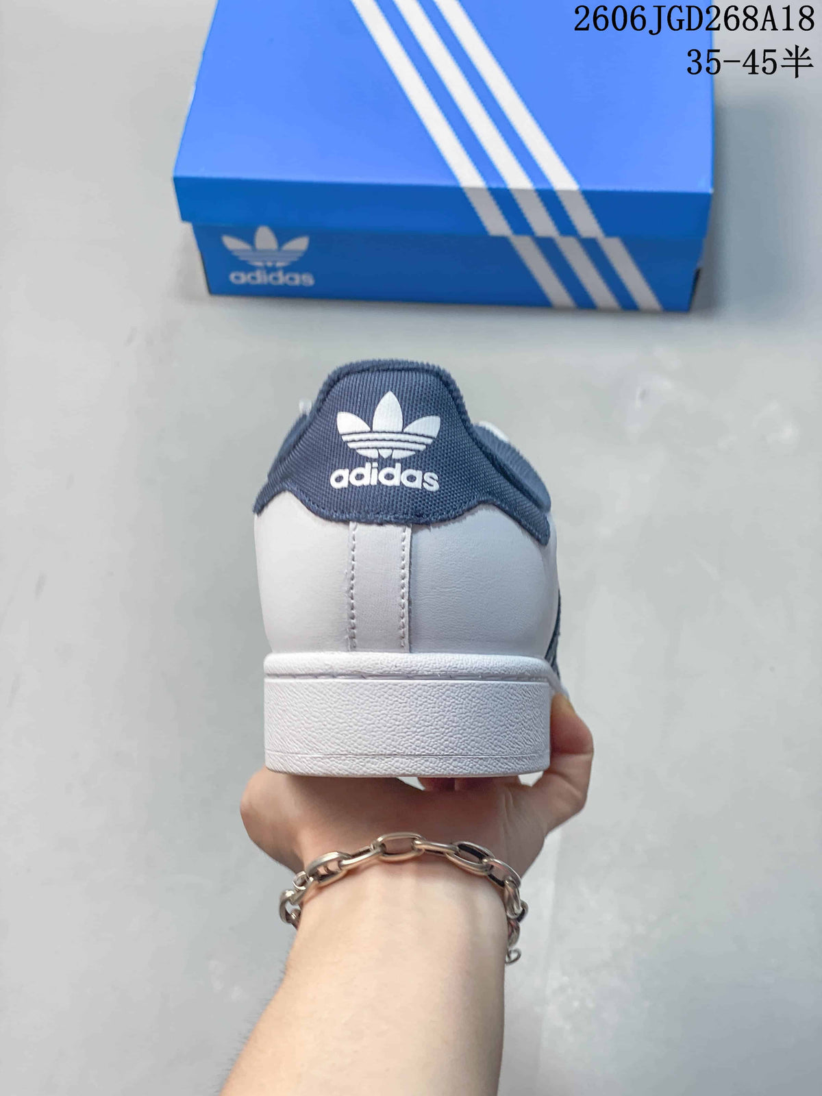 Rear view of a white Adidas Superstar sneaker with navy heel tab.