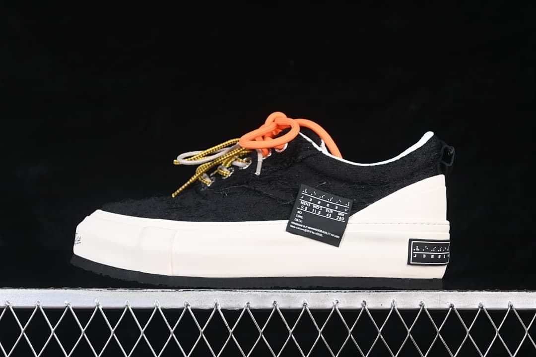 Side view of black low-top sneakers with a white platform sole and multicolor laces