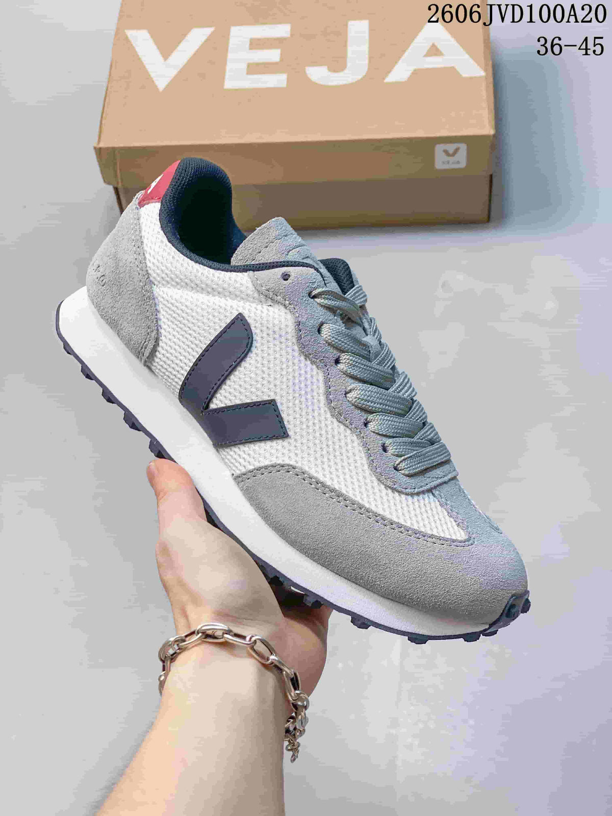 Close-up of a white and grey low-top sneaker with navy V-shaped side logo