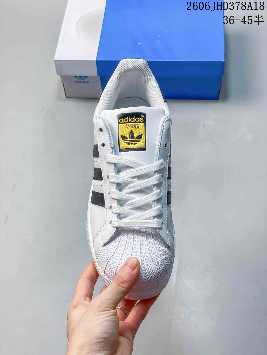 Front view of a white Adidas Originals Superstar sneaker with white laces and a shell toe.