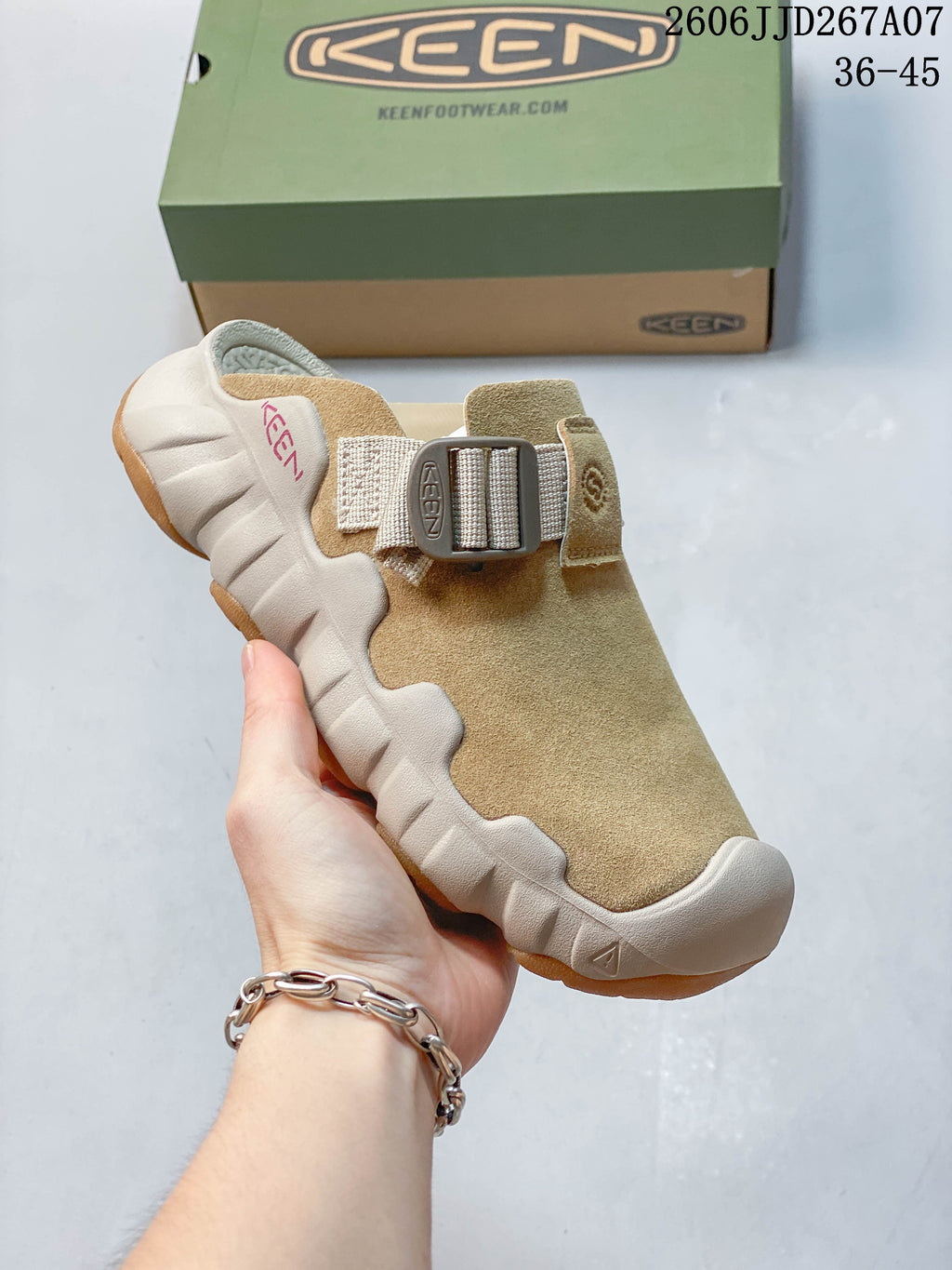 Side view of a tan clog mule with a broad strap and sculpted outsole