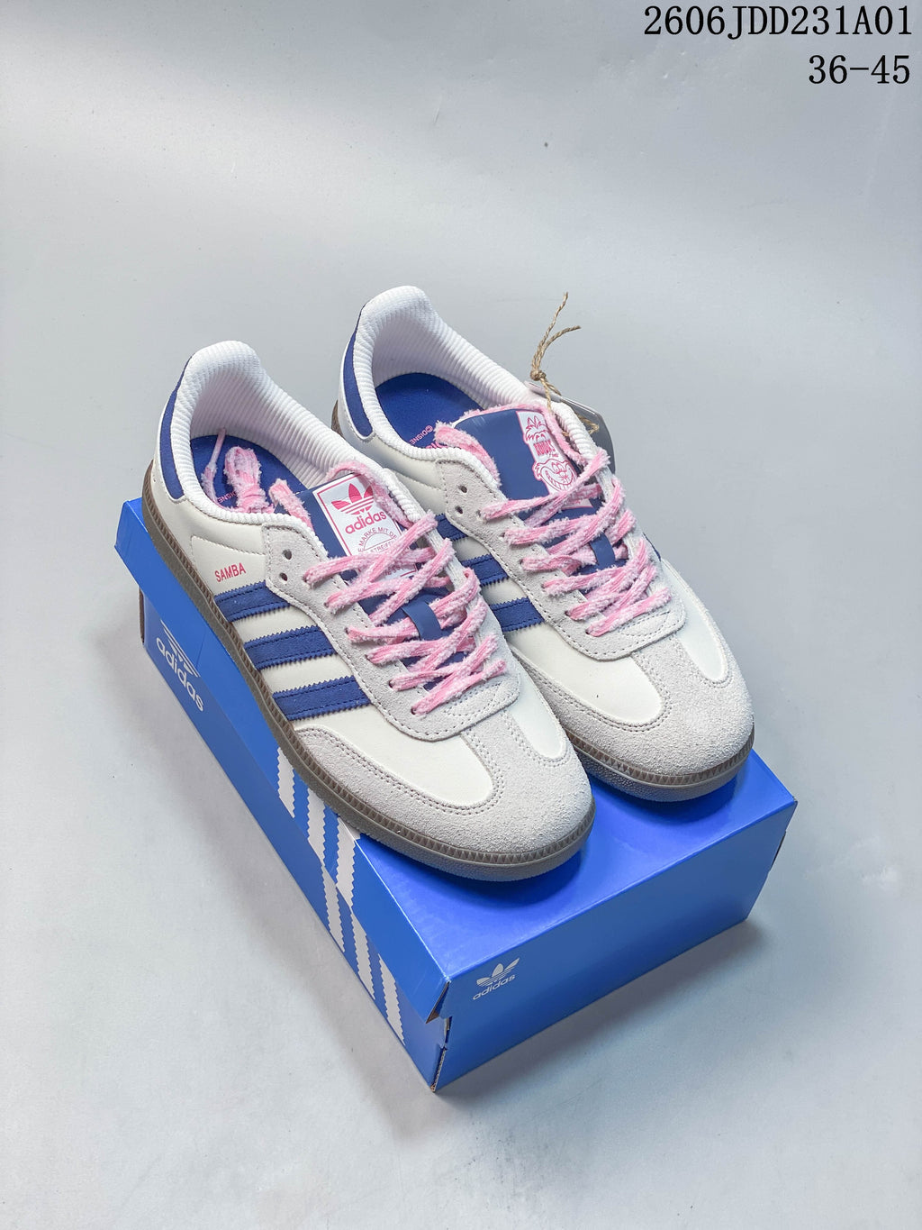 Adidas Samba OG sneakers in off-white, blue, and pink, shown from above on a blue box