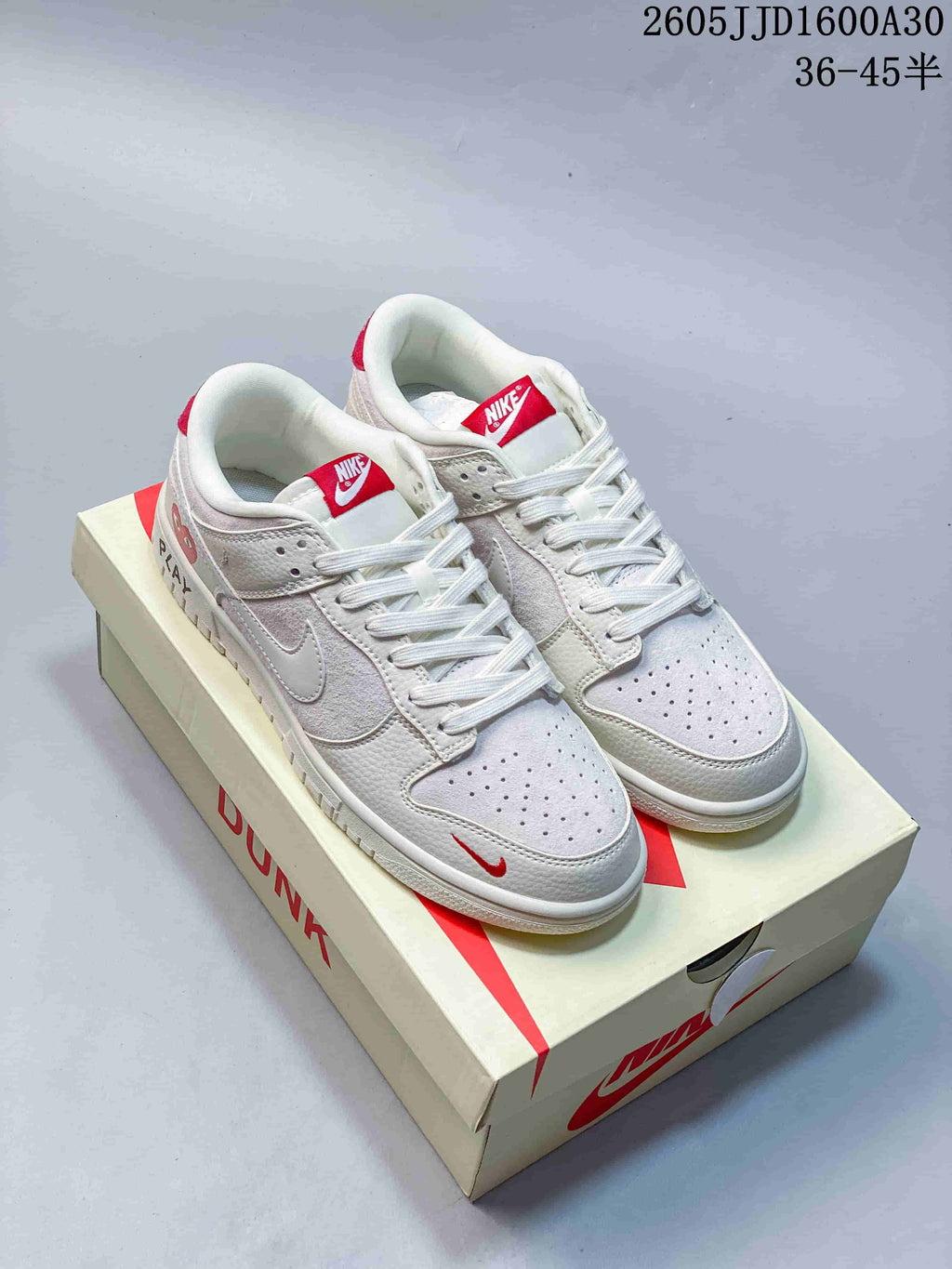 Pair of off-white and red low-top Nike SB Dunk sneakers displayed on a shoebox