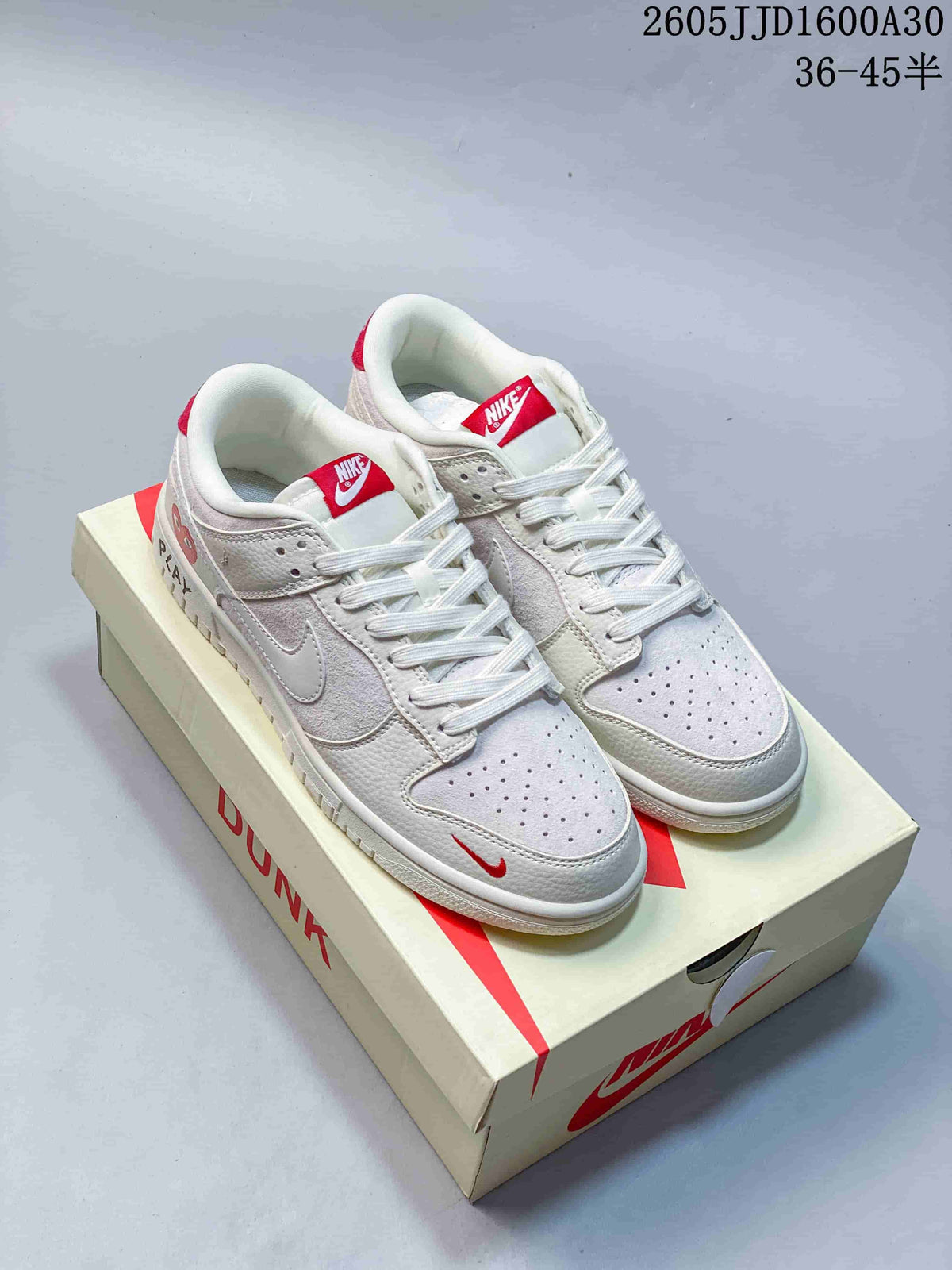 Pair of off-white and red low-top Nike SB Dunk sneakers displayed on a shoebox