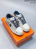 Pair of cream and gray Nike SB Dunk Low sneakers with patterned panels and dark laces on an orange shoe box
