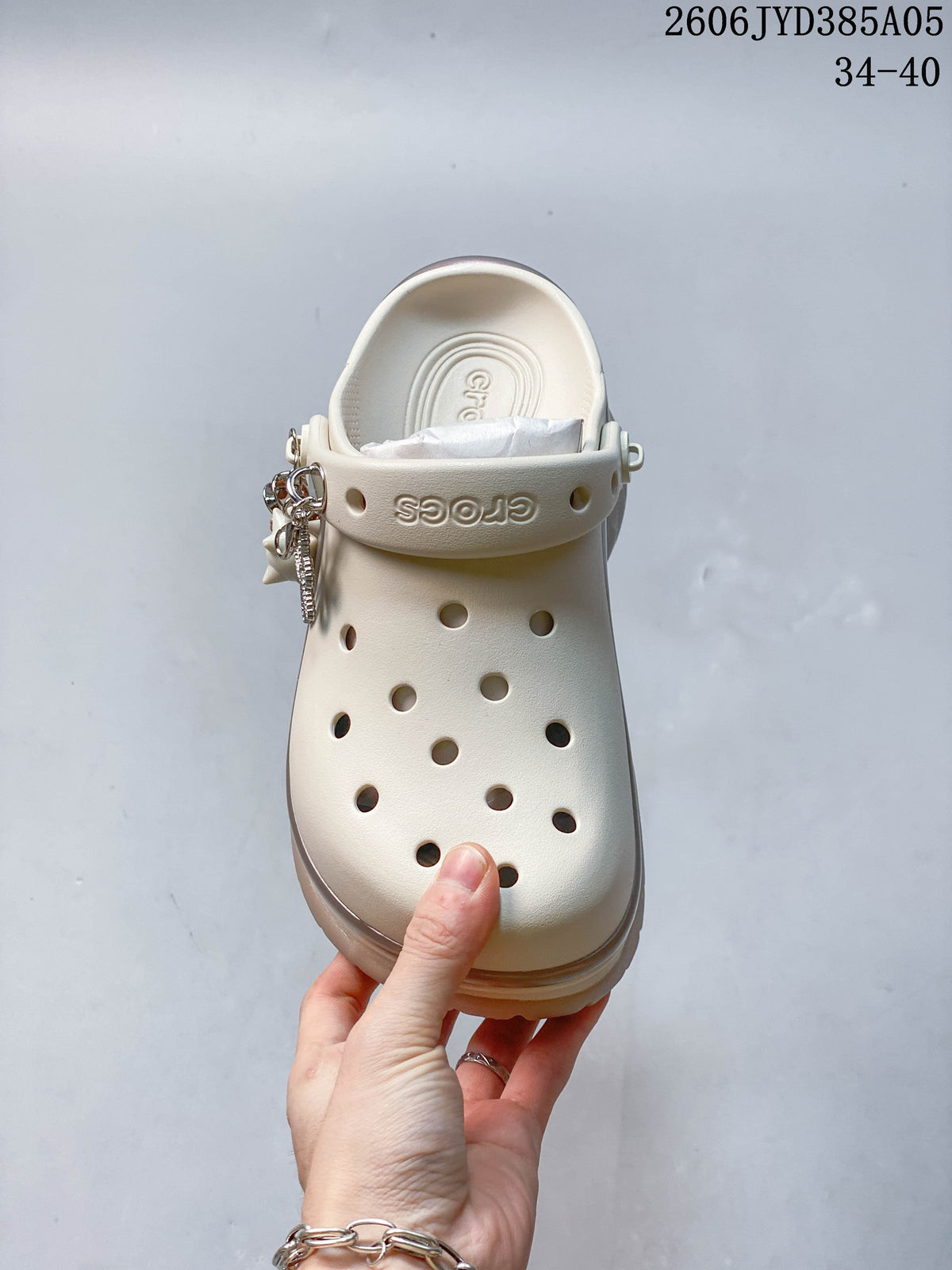Top view of an ivory perforated clog with decorative charms on the strap