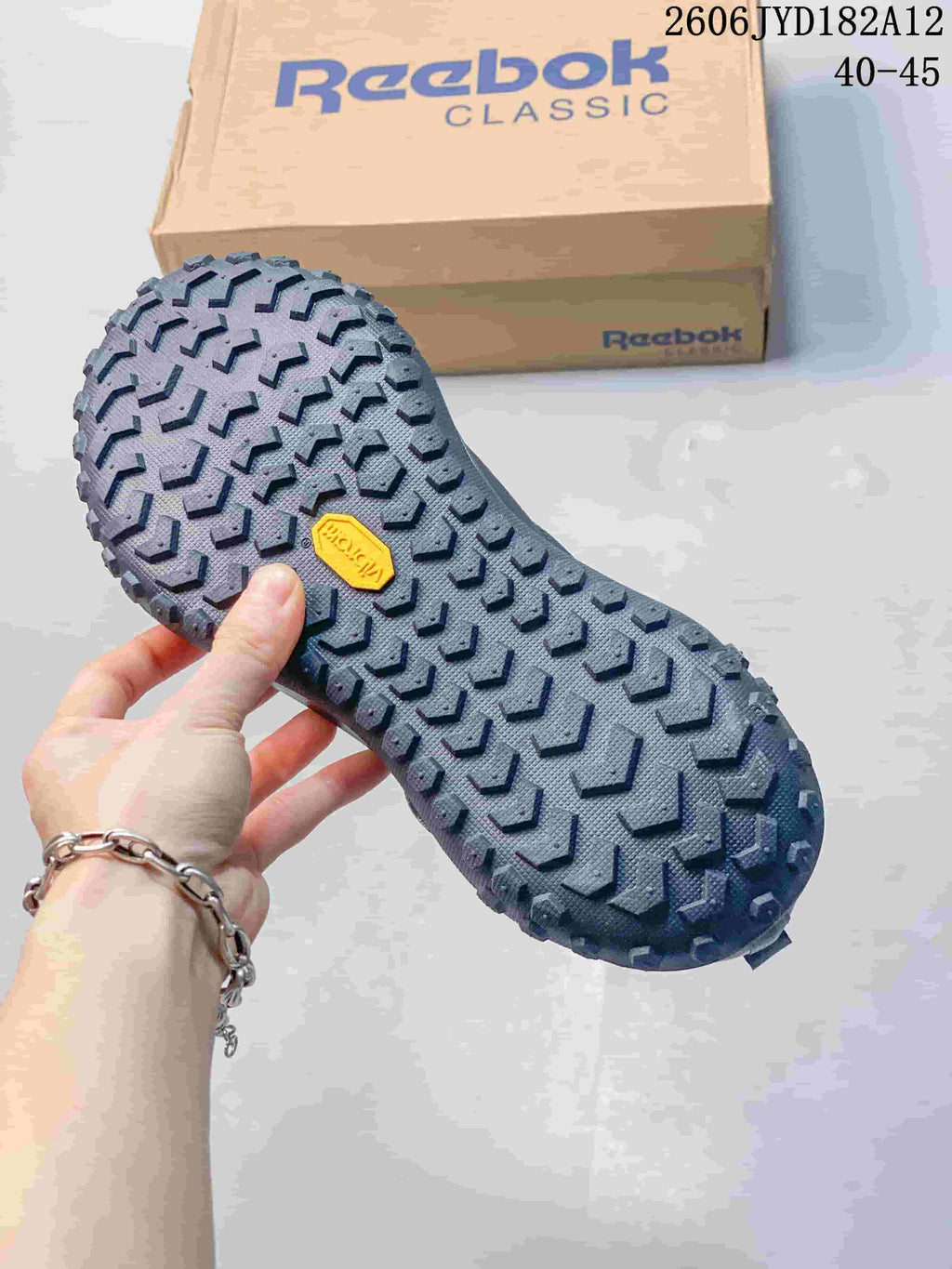 Close view of the patterned tread on a charcoal sneaker outsole.