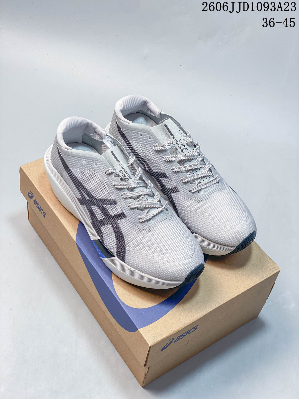 Light gray ASICS running shoes with dark side logos, photographed on a shoebox