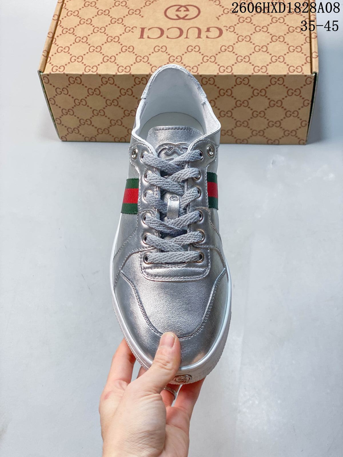 Front view of a silver lace-up sneaker with gray laces and a green-and-red side stripe.