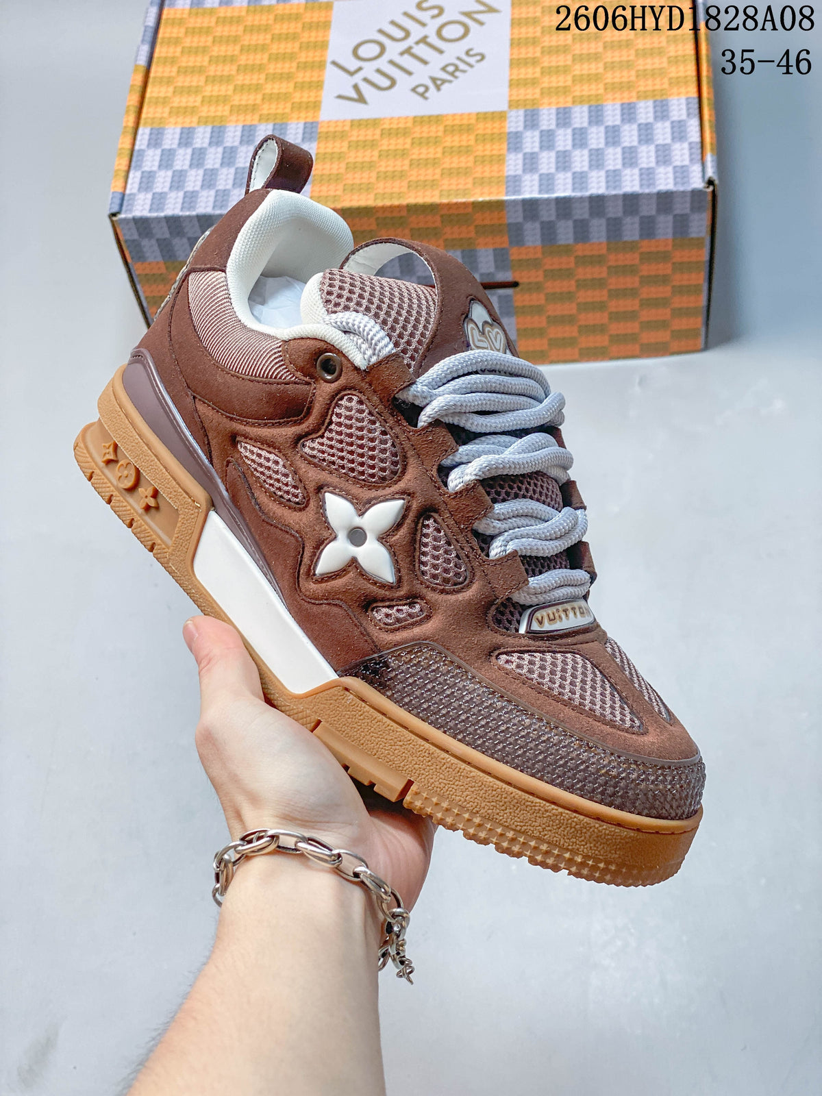 Close-up of a brown low-top sneaker showing its layered panels, mesh details, and side emblem.