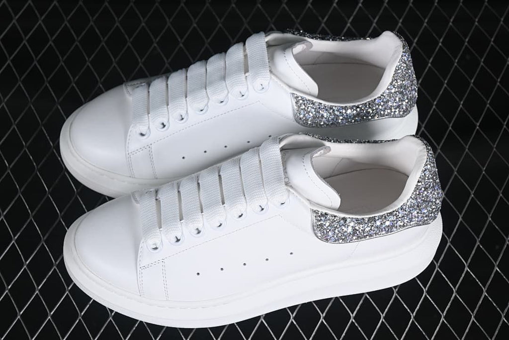 Pair of white low-top sneakers with glitter heel panels.