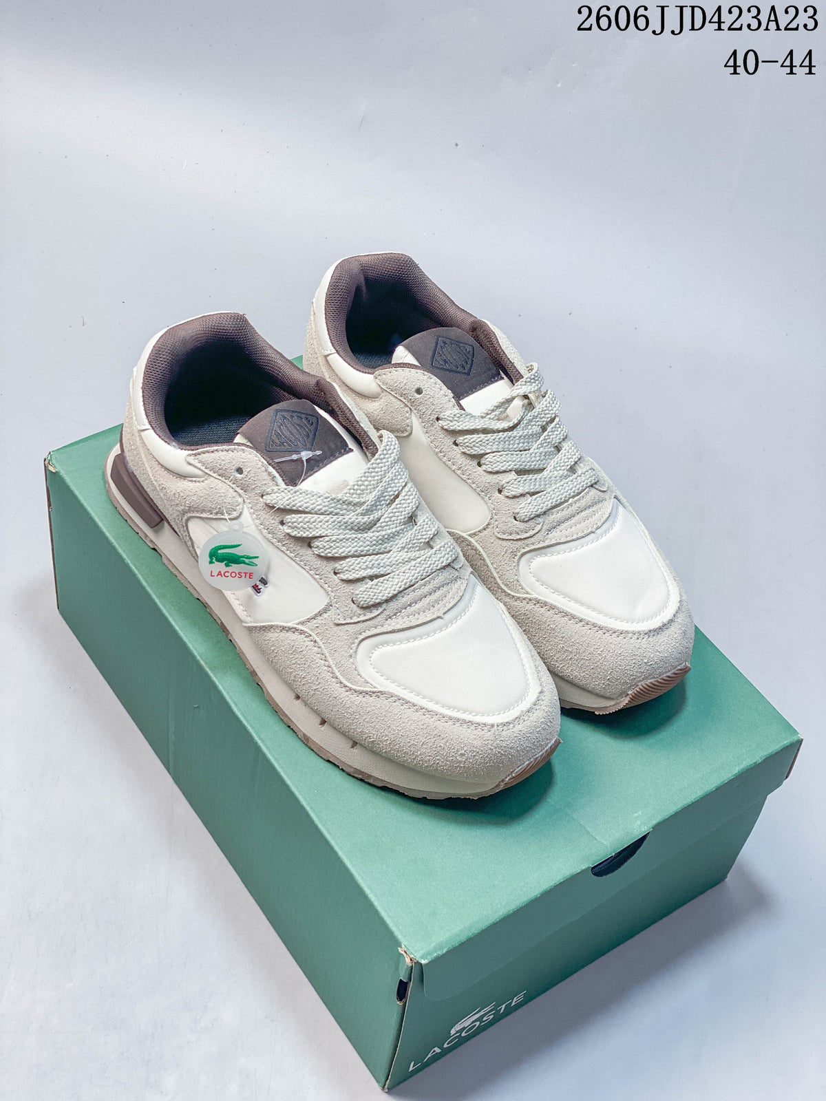 Pair of cream and light beige low-top lace-up sneakers displayed on a green shoe box