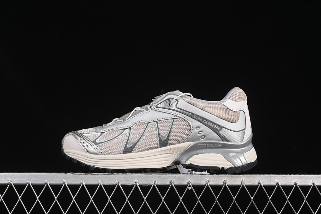 Side profile of silver and off-white Salomon XT-Whisper sneakers on a dark background.