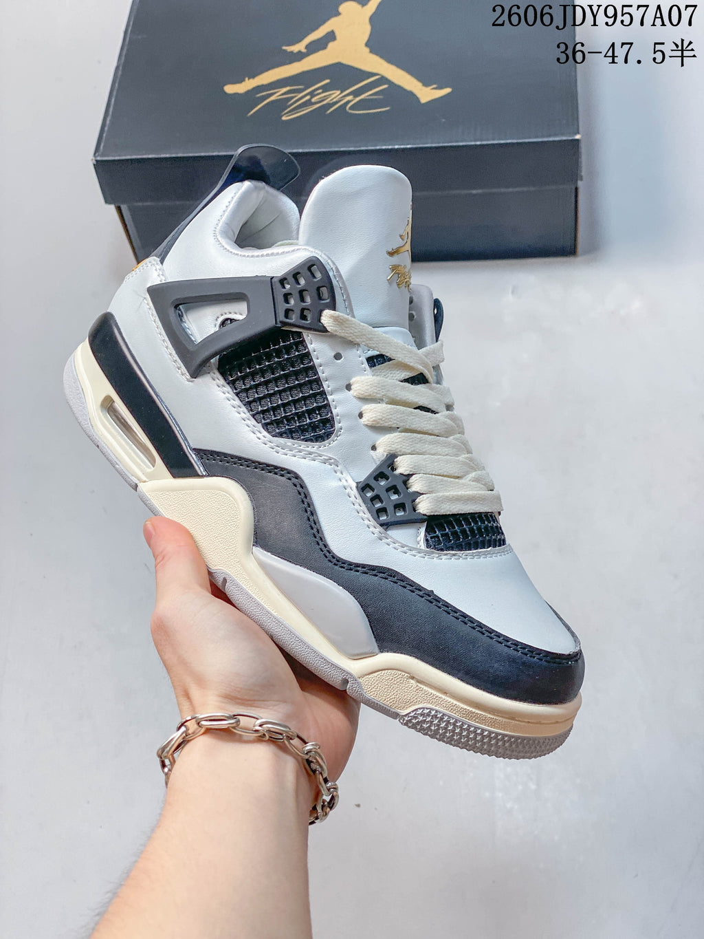 Angled side view of a white and dark-panel Jordan 4 sneaker
