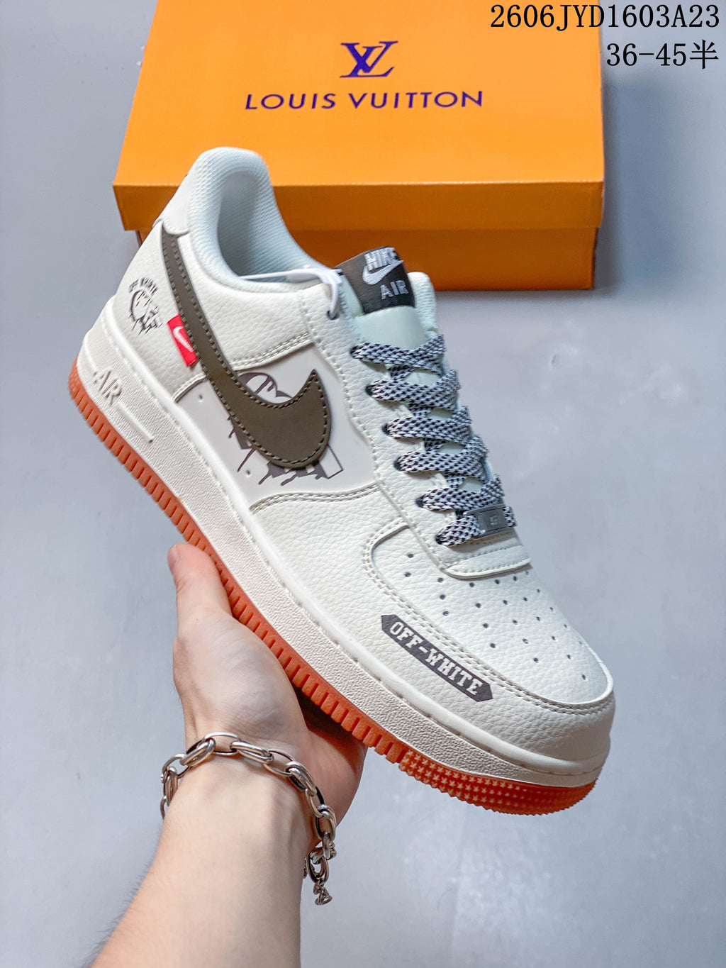 White low-top sneaker with a brown-gray Swoosh, black graphic details, and an orange outsole