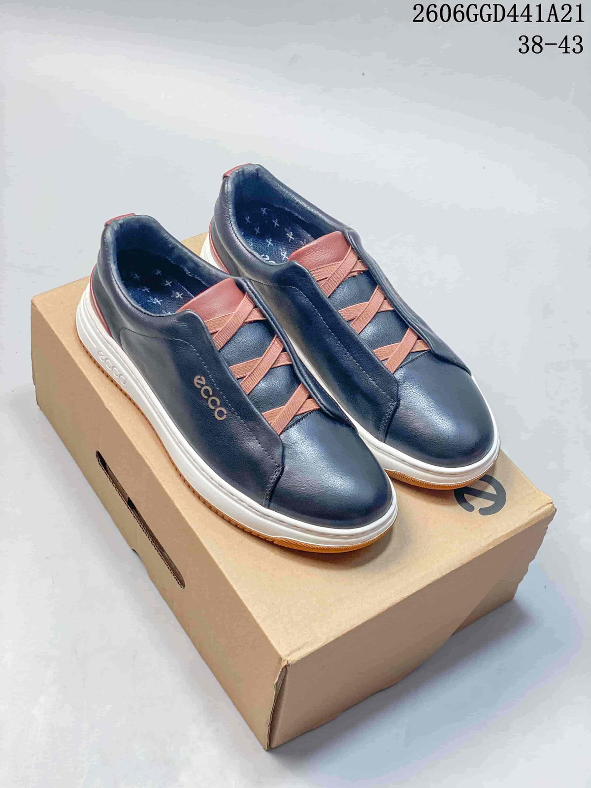 Pair of navy ECCO low-top sneakers with brown elastic cross-straps and white midsoles, shown on a shoebox.