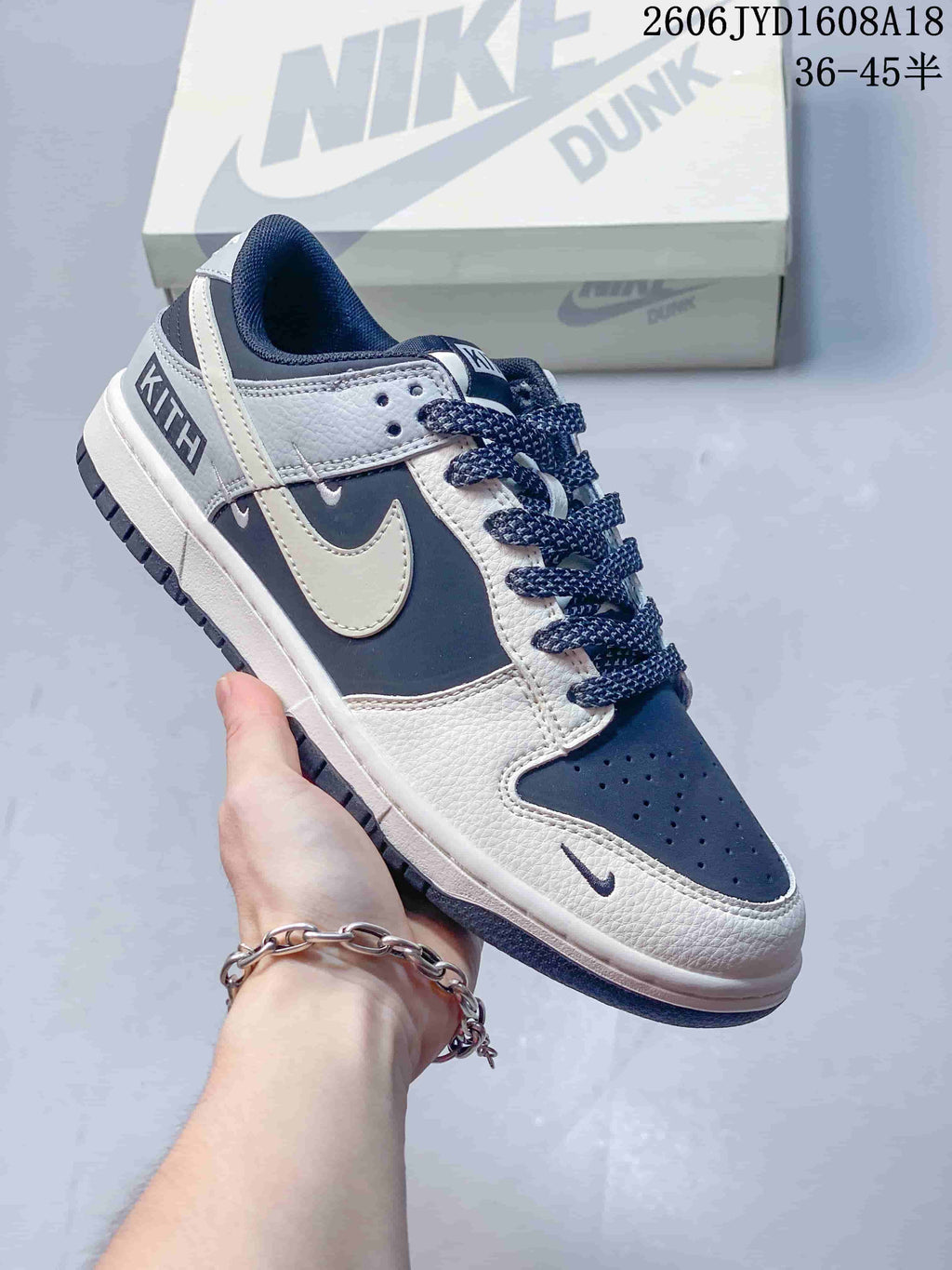 Angled side view of a navy, grey, and off-white low-top sneaker with visible Kith branding