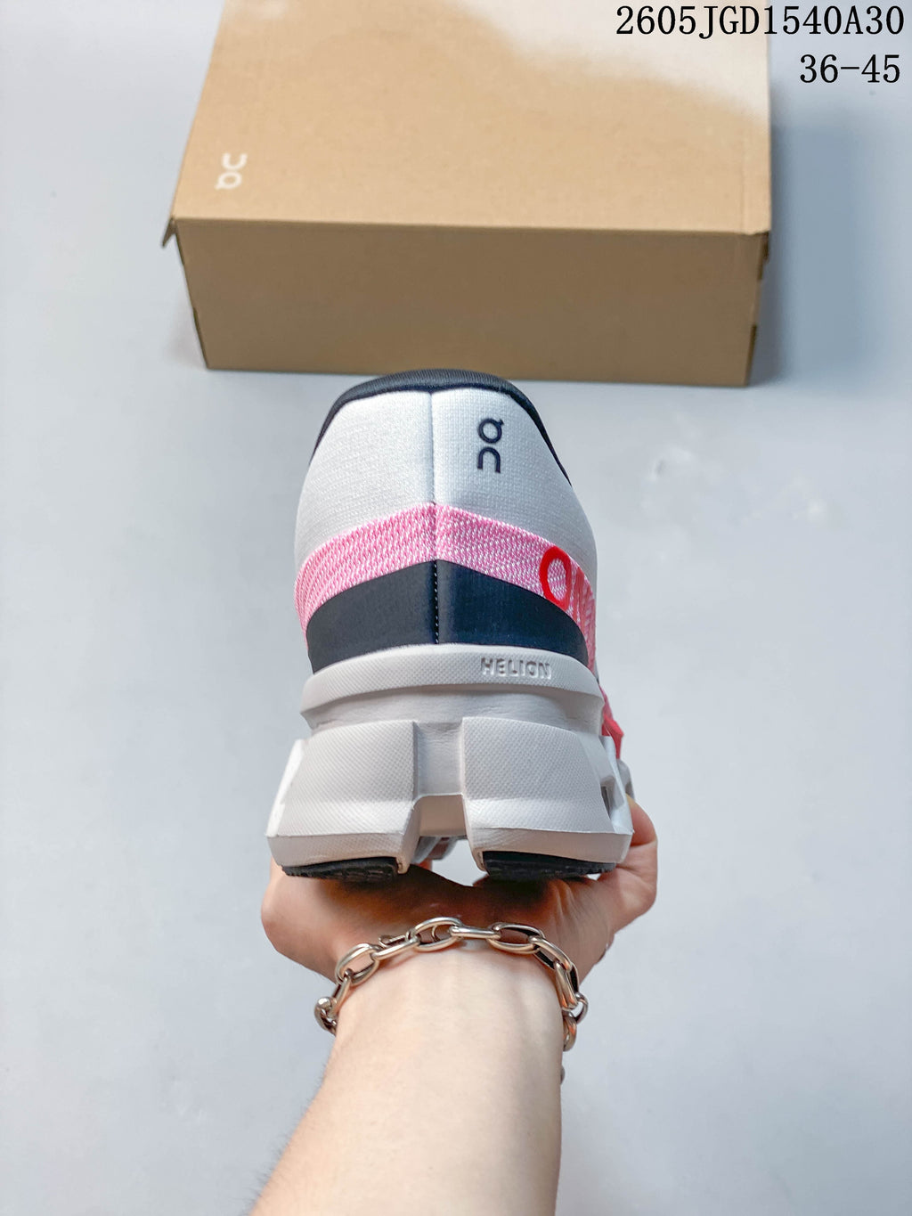 Rear view of a white running shoe with pink and navy heel accents