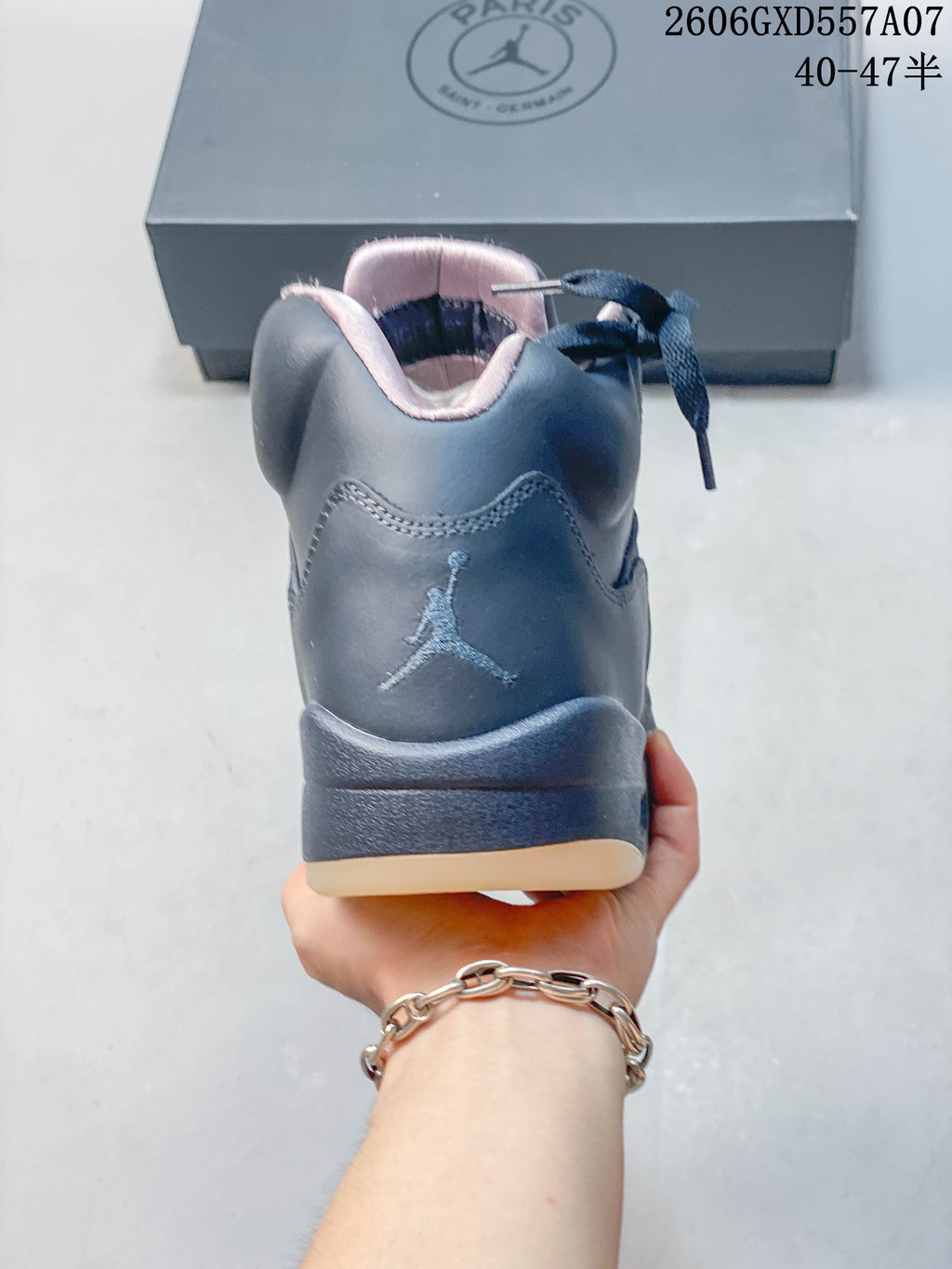 Rear view of a gray Jordan Air Jordan 5 sneaker with a Jumpman logo and pale pink collar lining.