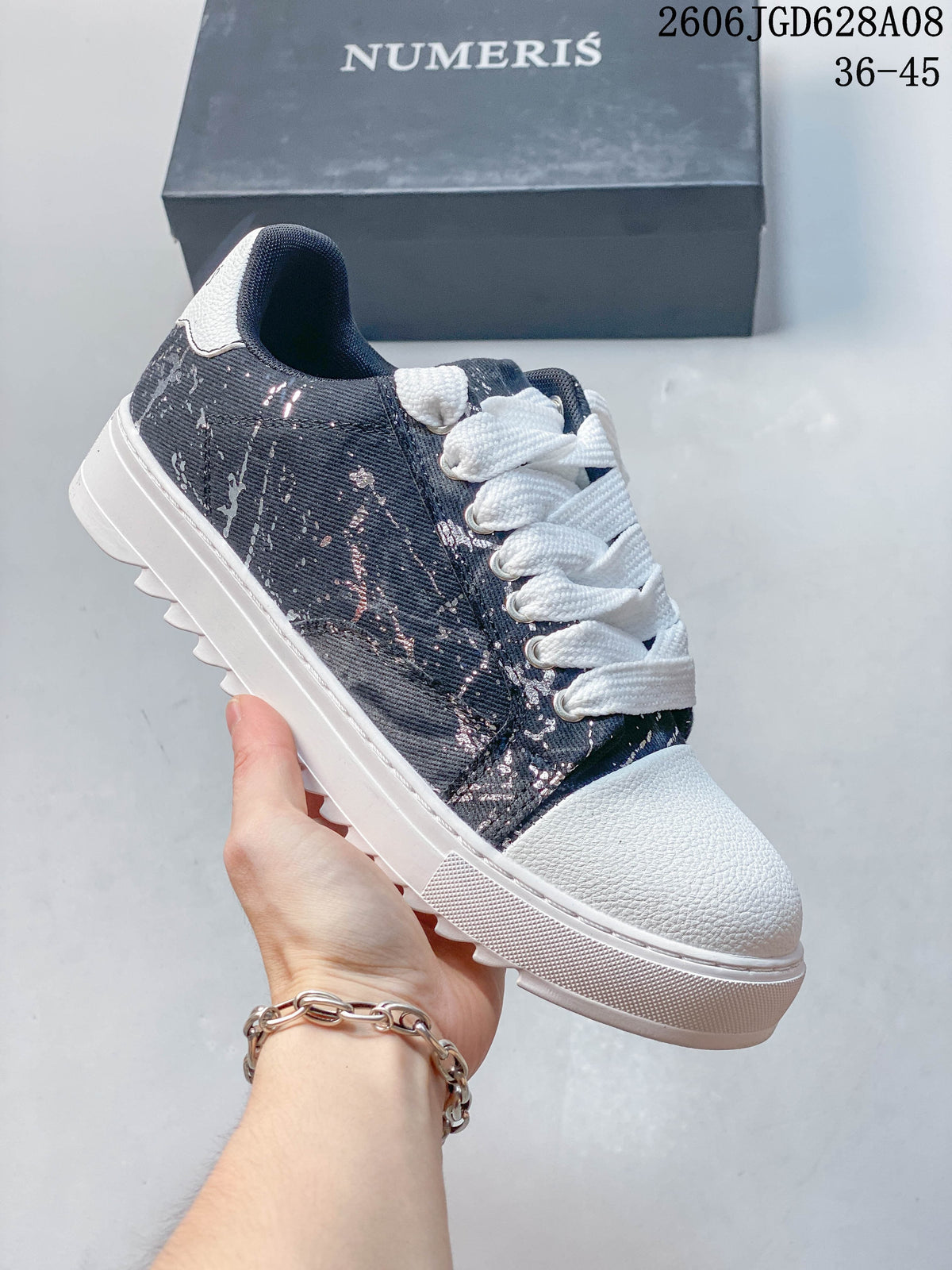Dark sneaker with a white toe and sole and a speckled printed side panel.