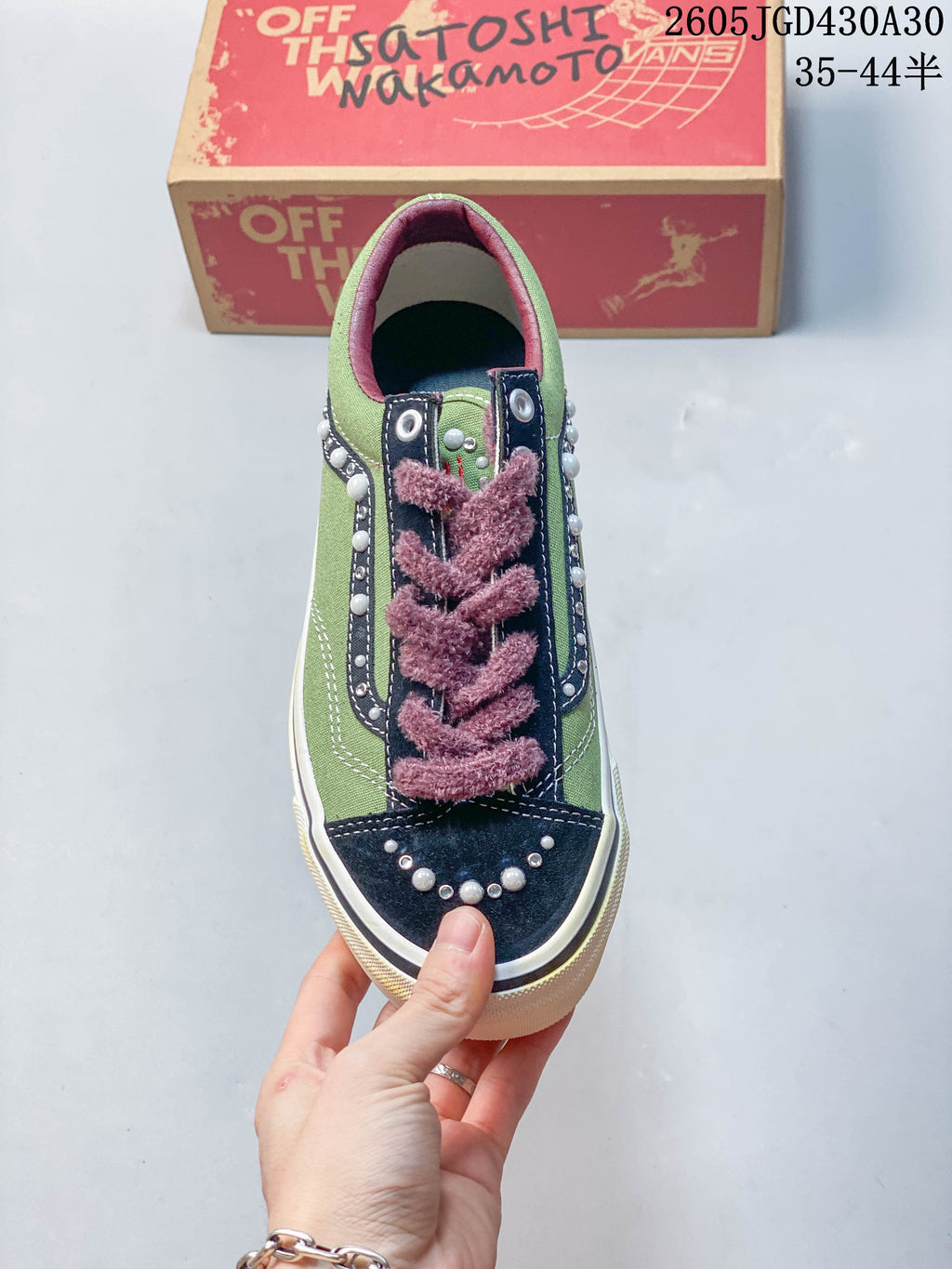 Top view of a green and navy Vans sneaker with pearl-like toe details and mauve laces.