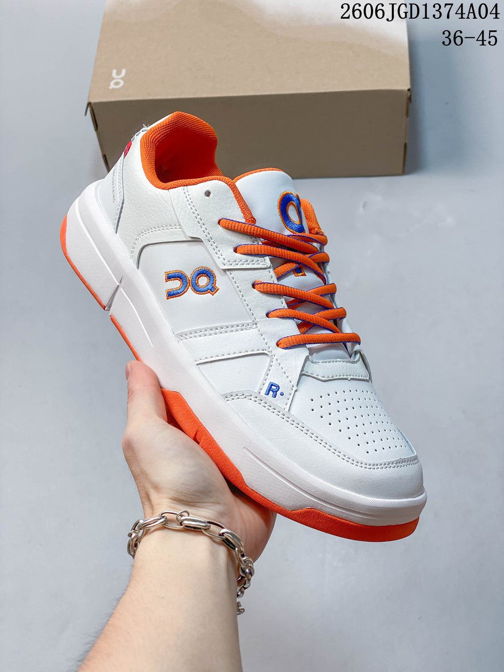 Side view of a white On THE Roger Clubhouse sneaker with orange accents and perforated toe