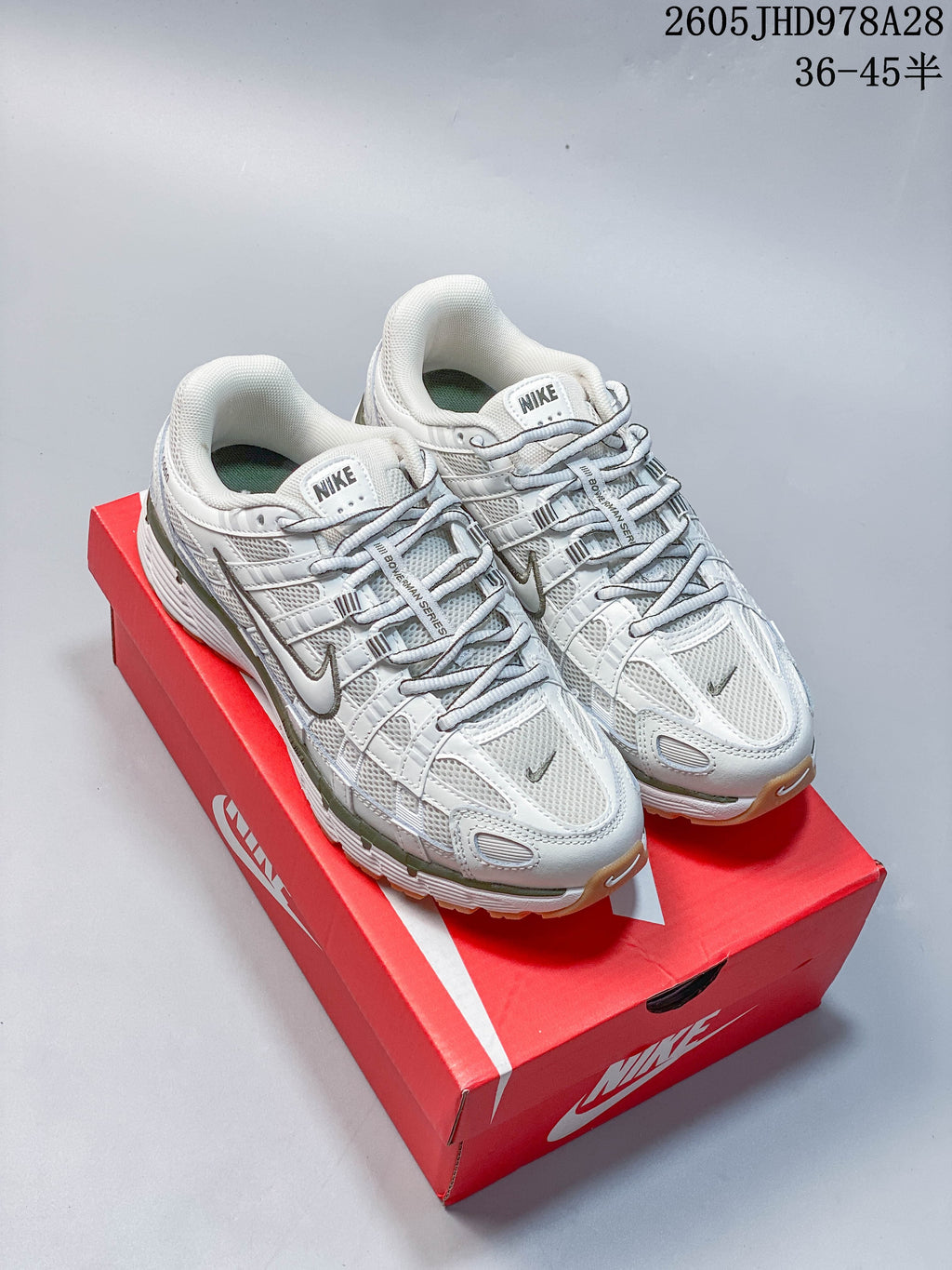Pair of white and olive-accented Nike Initiator shoes on a red shoebox