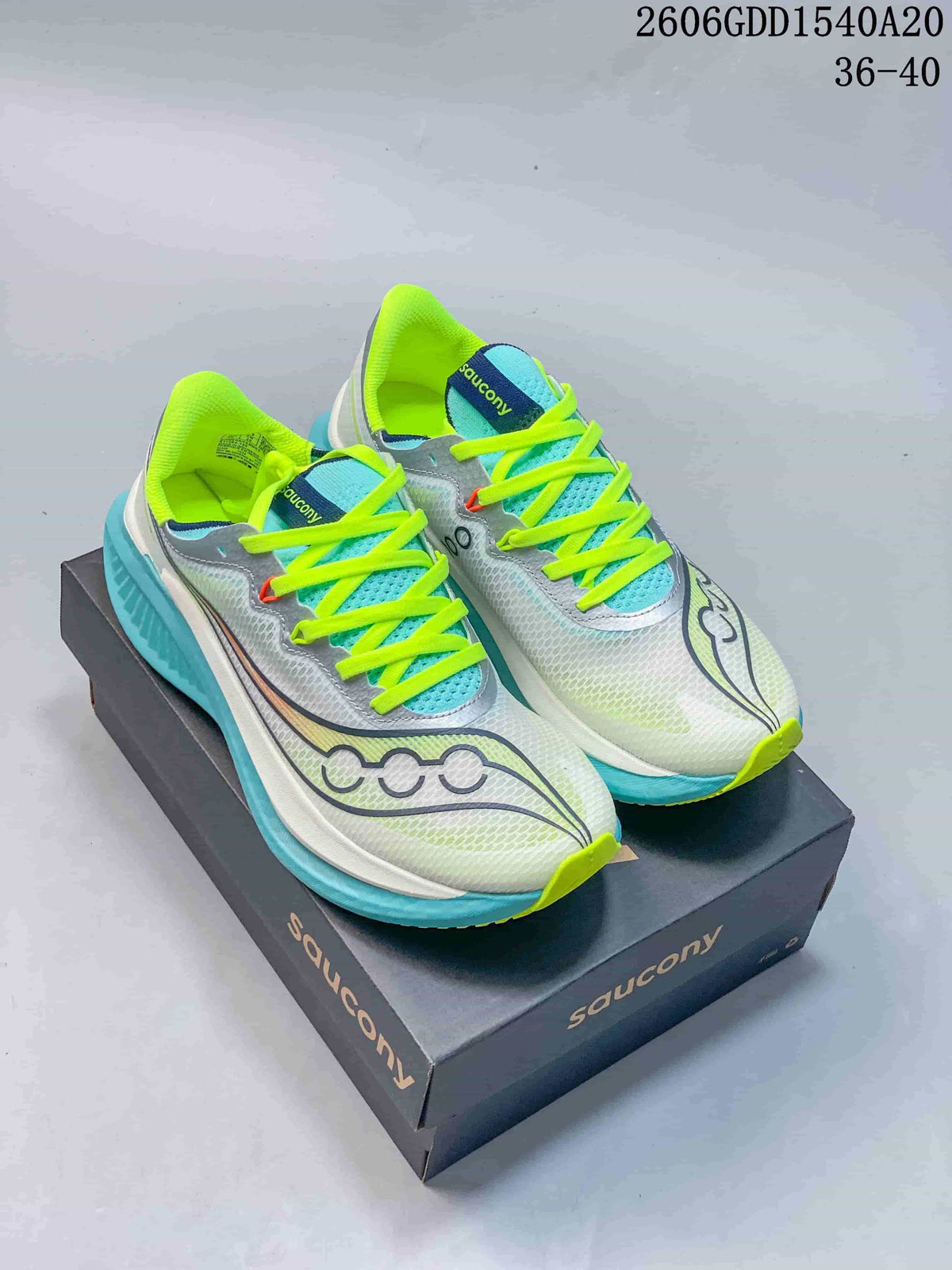 Pair of light-colored Saucony running shoes with turquoise and neon yellow-green accents on a branded box.