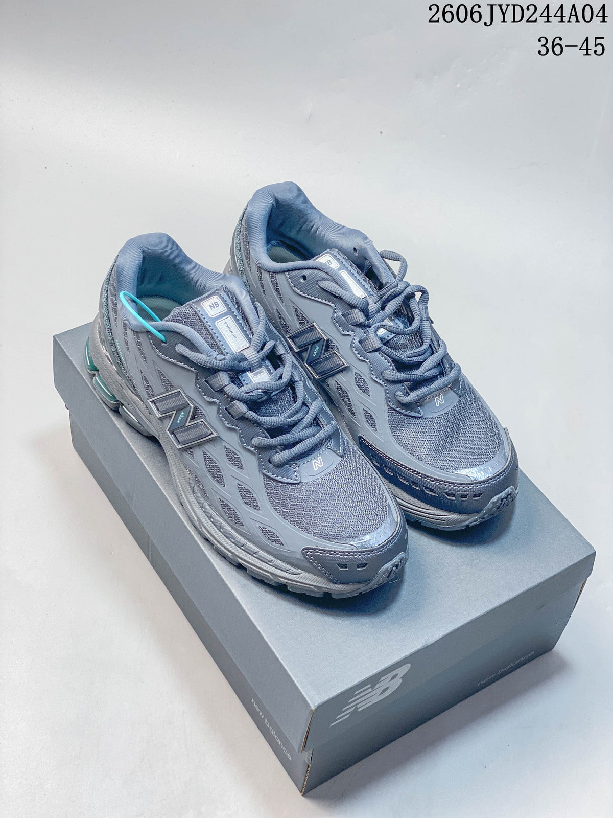 Pair of gray New Balance 1906R sneakers with teal accents displayed on a shoebox