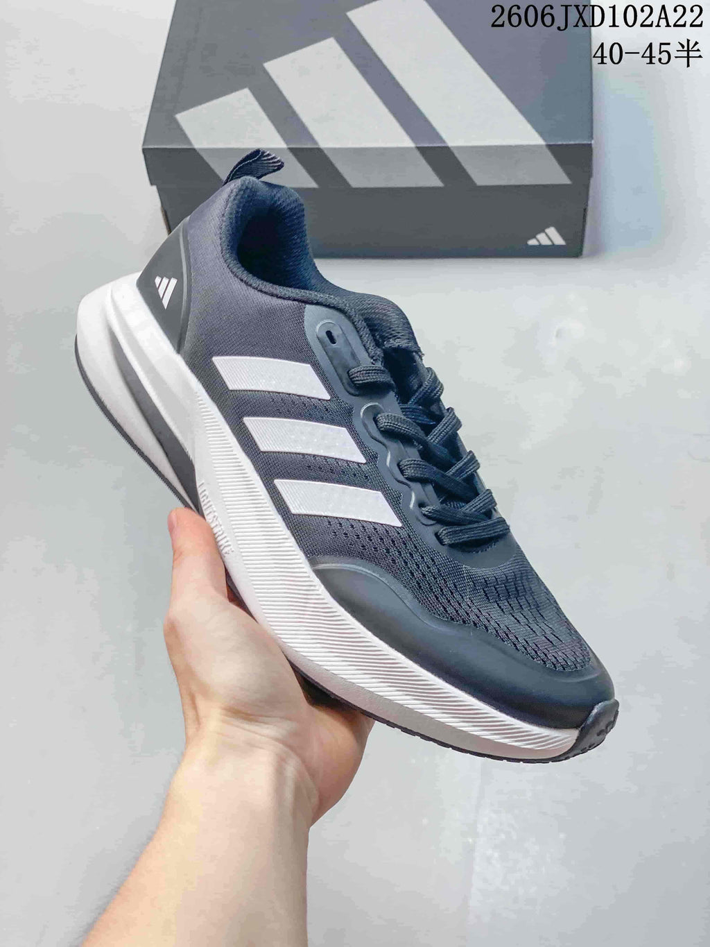 Side view of a dark gray Adidas sneaker with light stripes and a thick white sole.