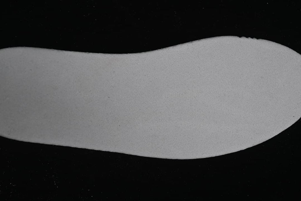 Light-colored shoe-shaped piece shown separately against a dark background