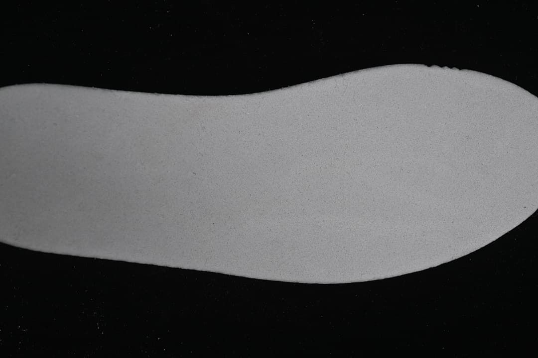 Light-colored shoe-shaped piece shown separately against a dark background