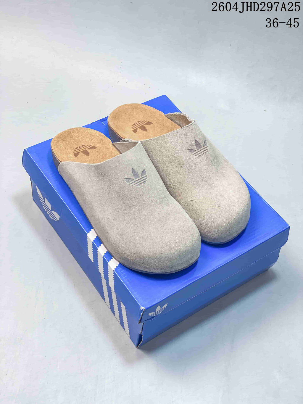 Light neutral Adidas Originals Adimule closed-toe mule slippers on a blue box