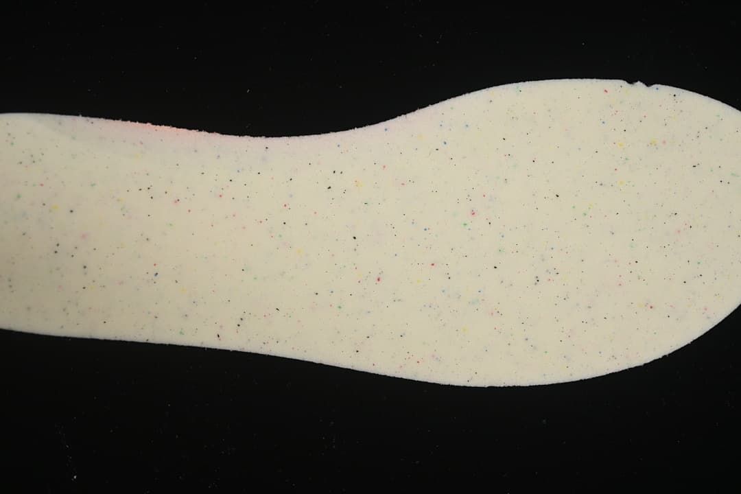 Close-up of a light-colored shoe insole with multicolored speckling.