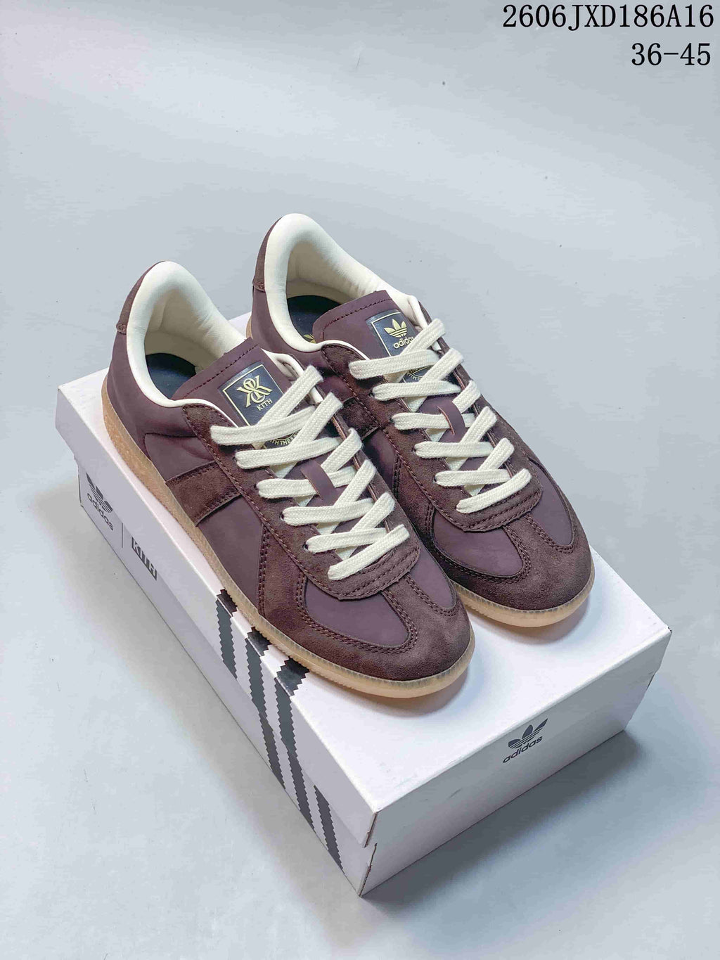 Pair of purple-brown adidas BW Army low-top sneakers with cream laces on a shoebox