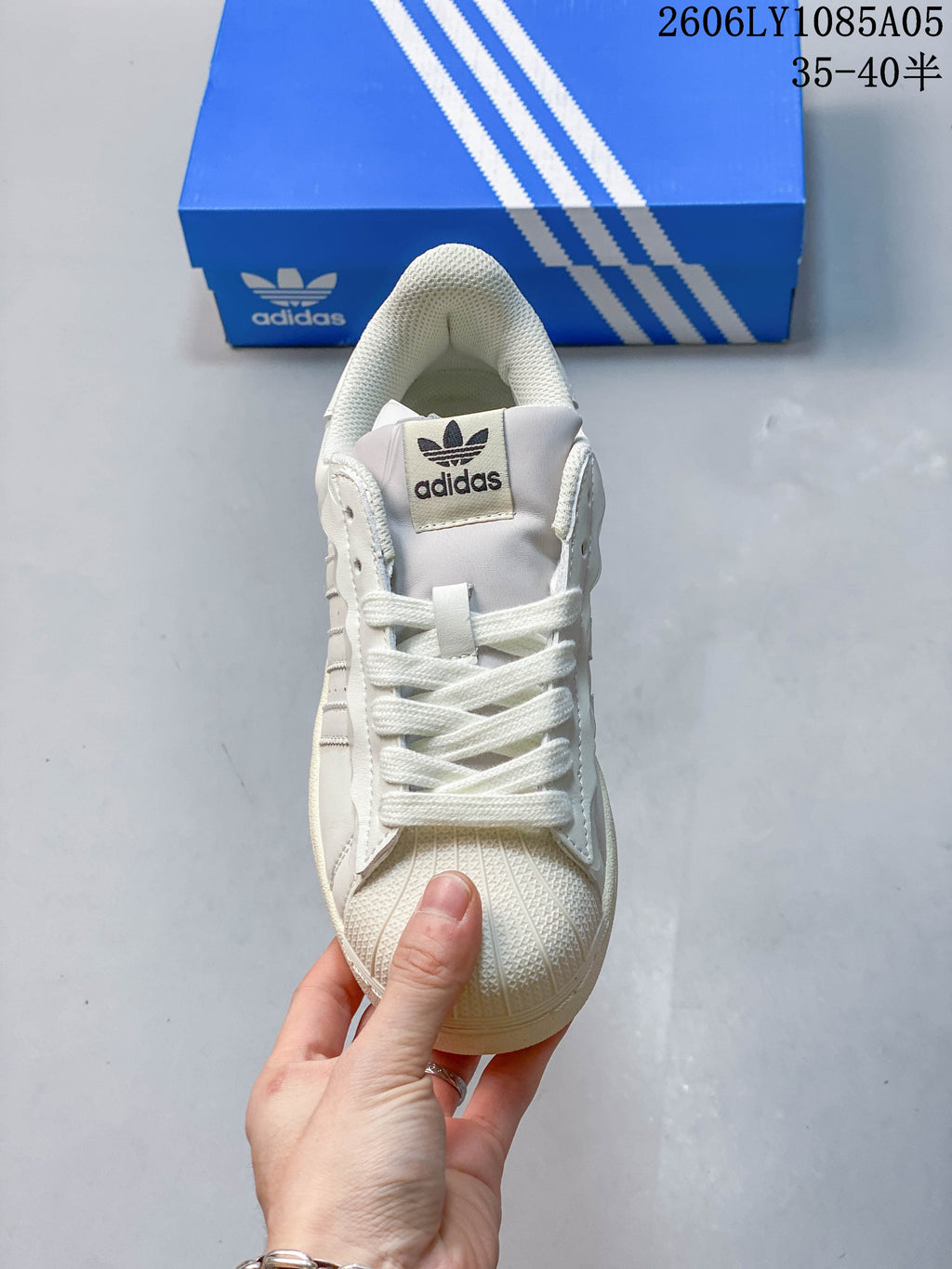Front view of a cream Adidas Superstar sneaker with laces and shell toe