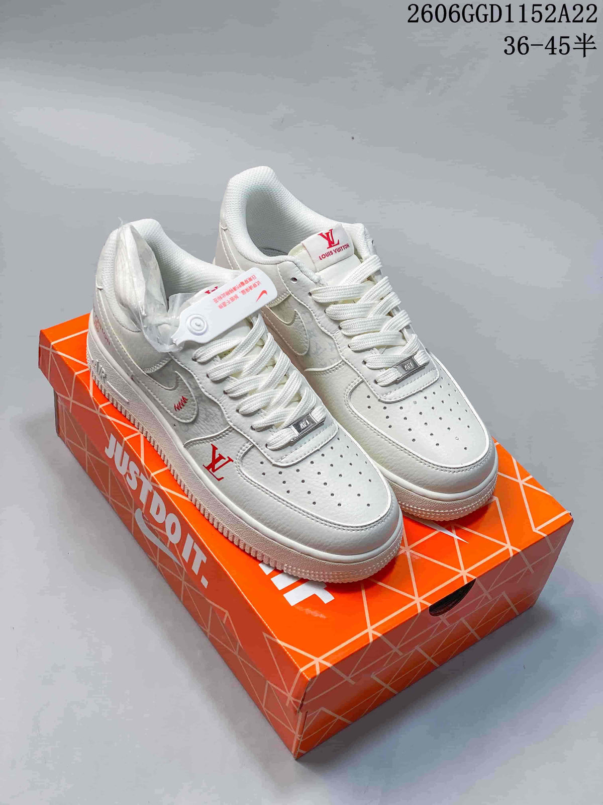 Pair of white low-top sneakers with white laces and red decorative details.