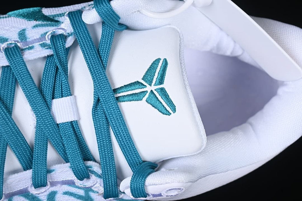 Close-up of teal Kobe logo on the white shoe tongue