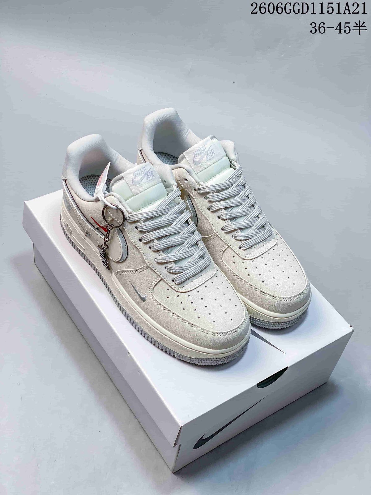 Pair of cream Nike Air Force 1 Low sneakers with pale blue details and a hanging charm