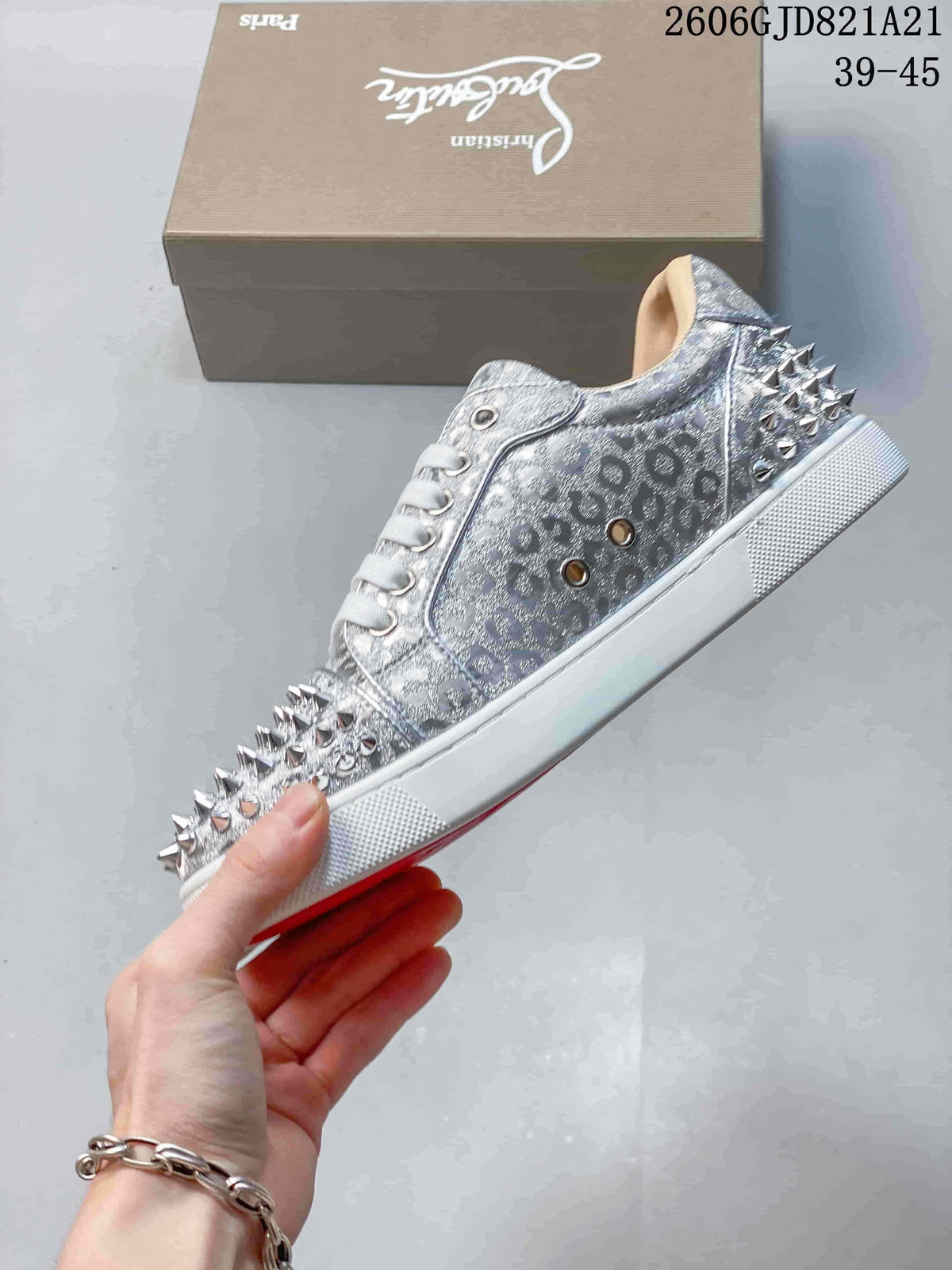 Side view of a silver patterned low-top sneaker with studded toe and heel