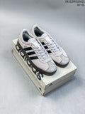 Pair of light grey Adidas VL Court Classic sneakers with black stripes and dark soles, shown on a shoe box