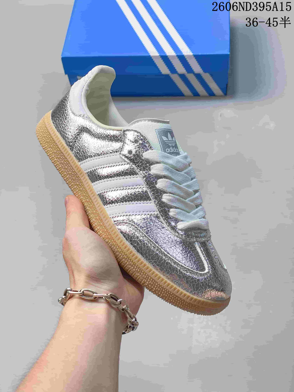 Side view of a silver metallic low-top sneaker with white stripes and gum-style sole