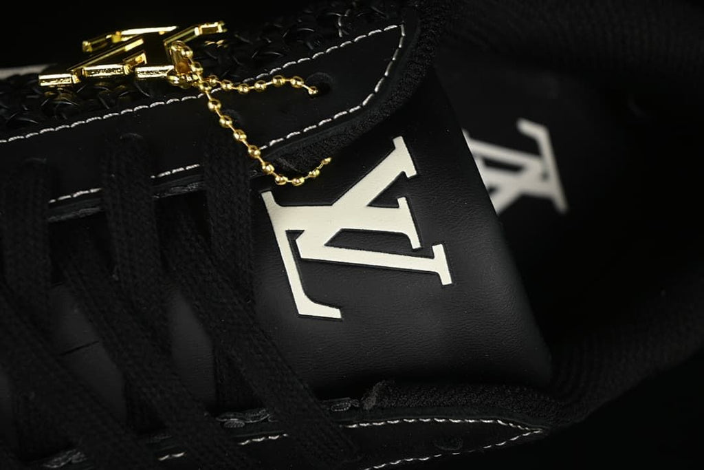 Close-up of the tongue logo, black laces and a gold-tone decorative charm
