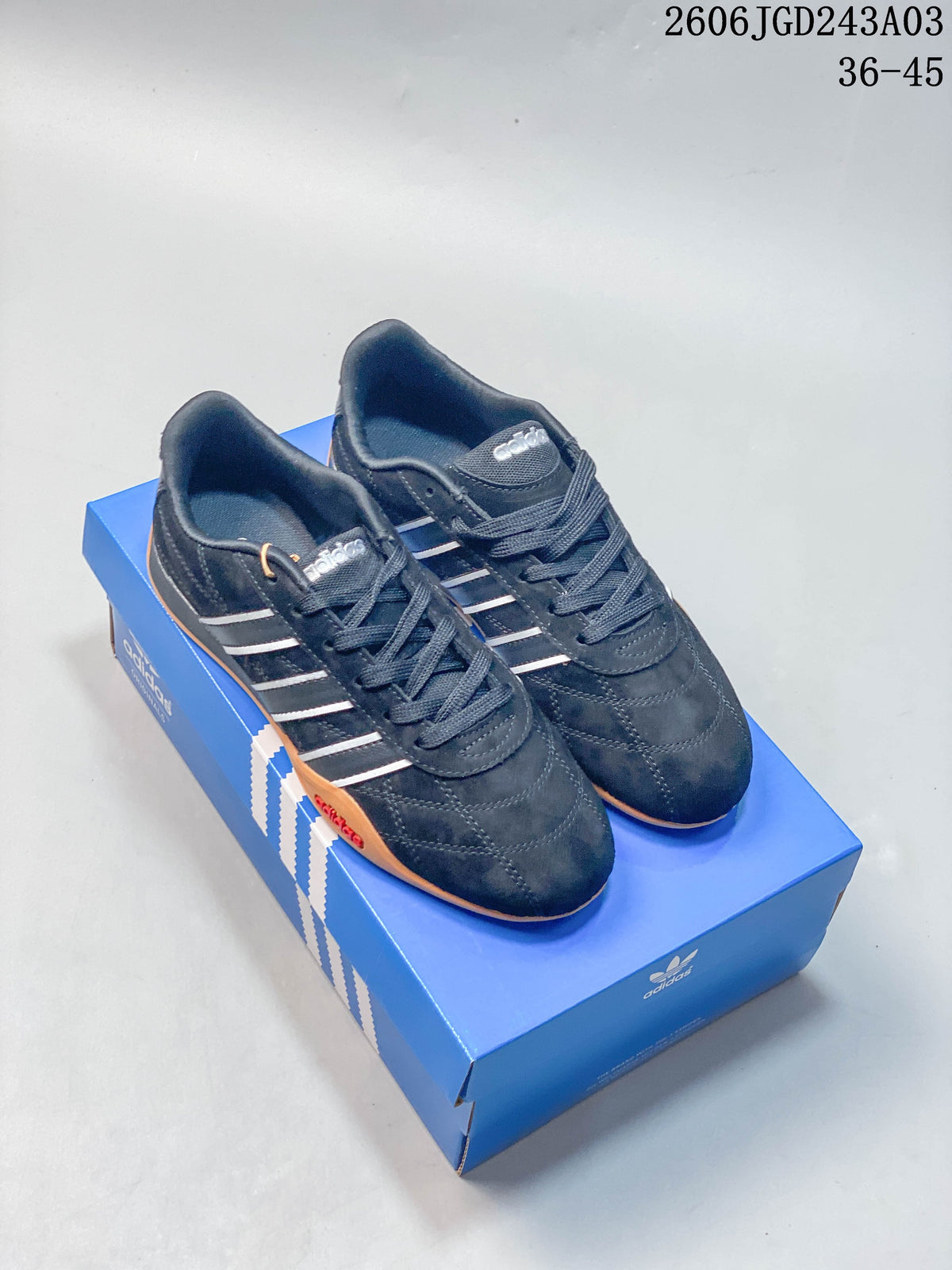 Pair of black adidas Adipista sneakers with light-colored stripes and gum-colored soles