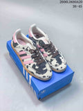 Adidas Samba OG sneakers with cow-print uppers, pink stripes, dark laces, and gum-colored soles on a blue shoebox