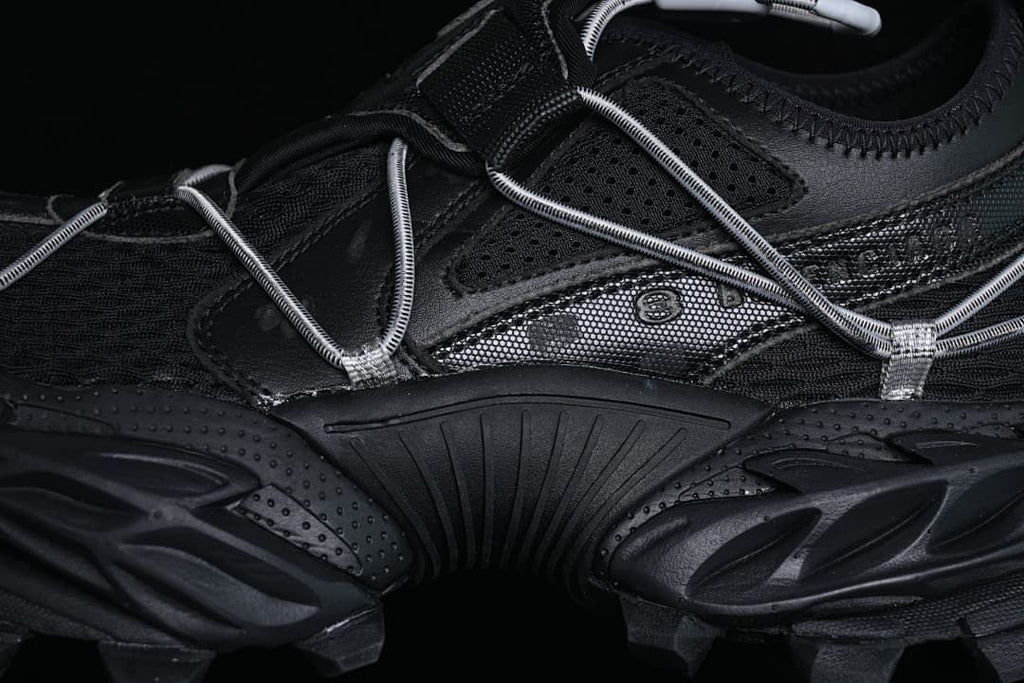 Close-up of layered side panels, cord lacing and chunky sole.