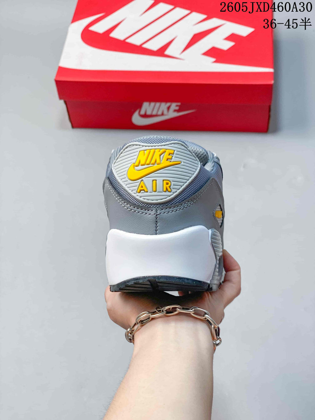 Rear view of the grey Nike Air Max 90 sneaker showing the heel branding and white midsole.