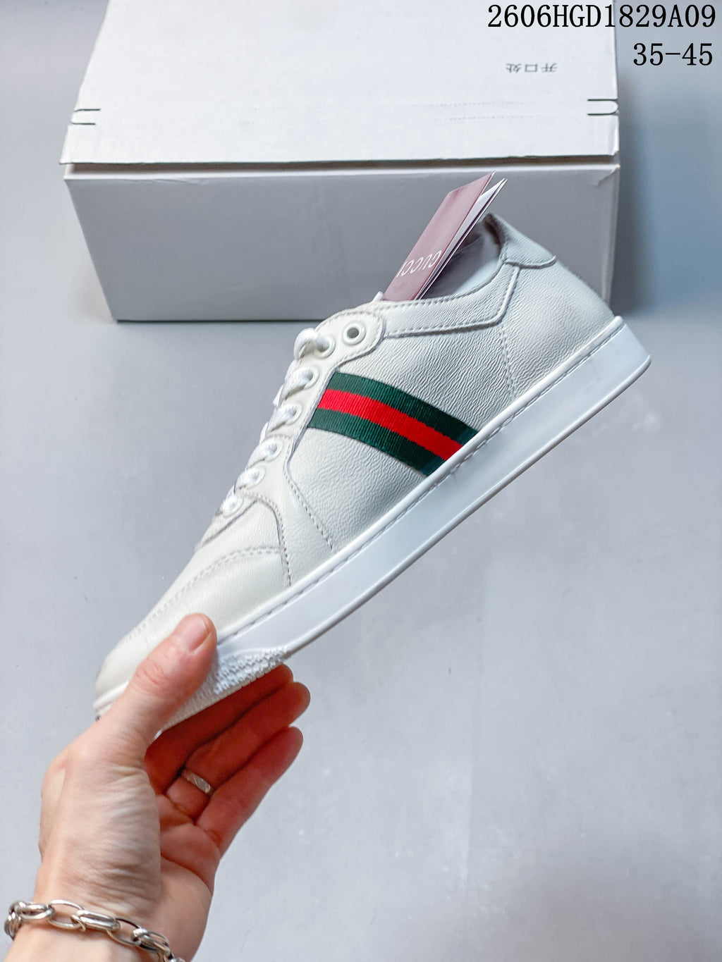 Side profile of a white sneaker with a red-and-green stripe and white sole.