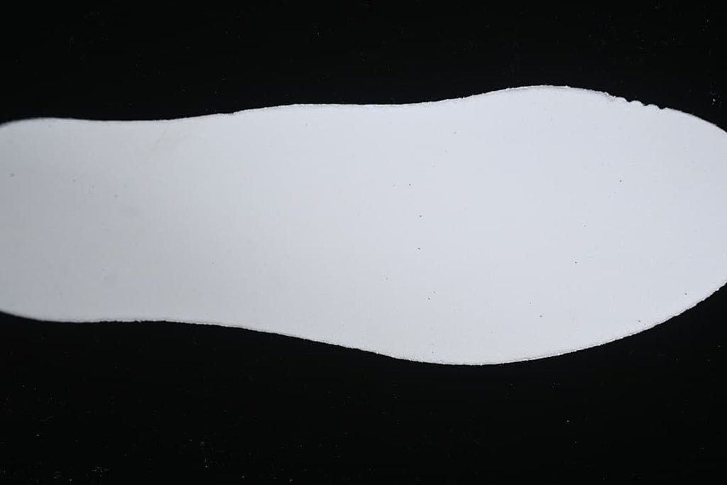 White shoe insole photographed on a dark background.