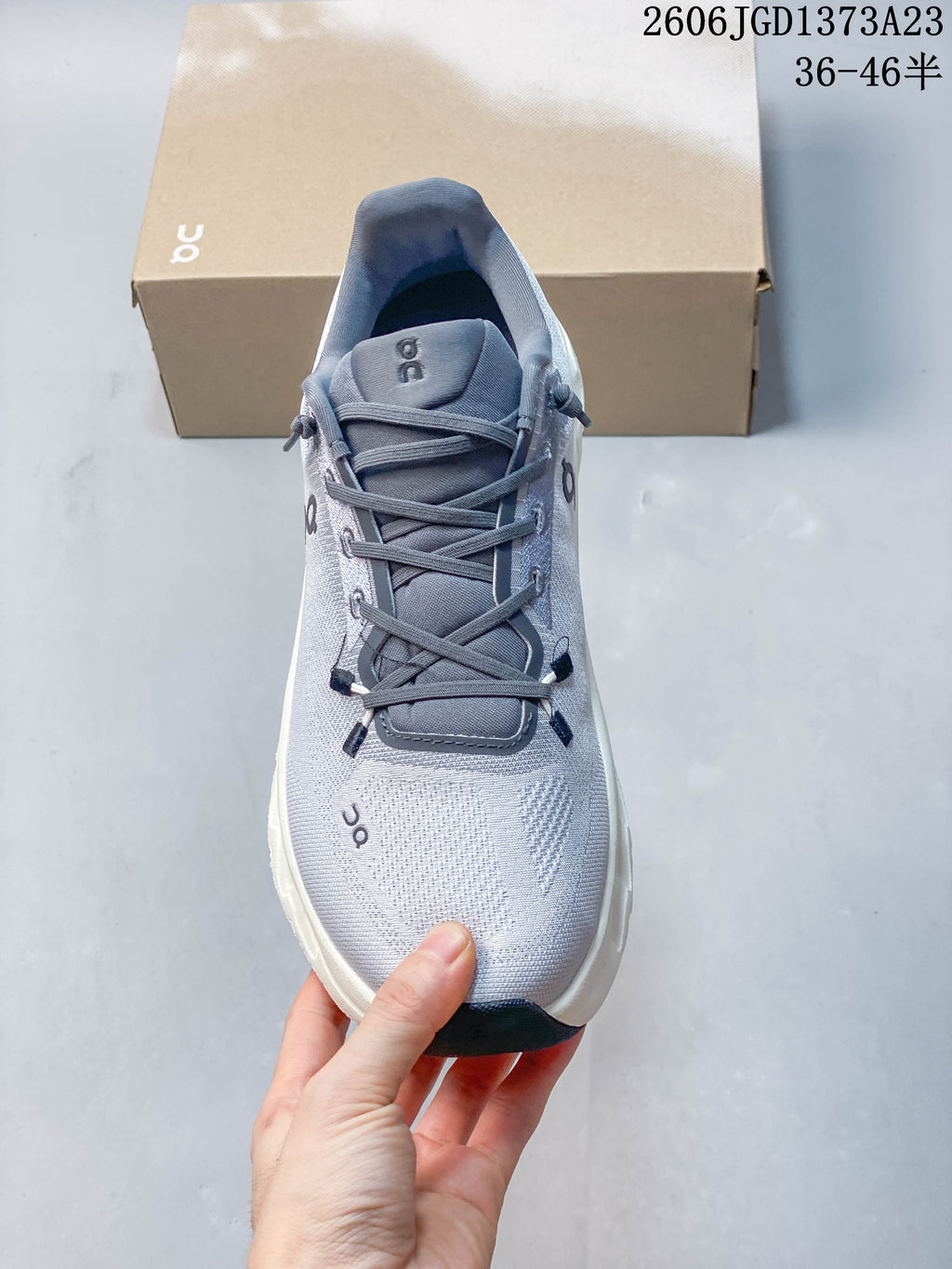Front view of a gray lace-up sneaker with a white toe and dark accents